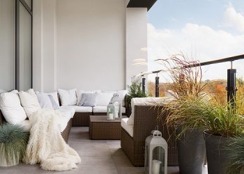 Elegant decorated balcony with rattan outdoor furniture, bright pillows and plants