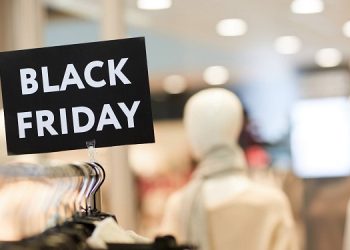 Background image of Black Friday sign on clothes rack with autumn clothes in shopping mall during sale season, copy space