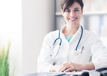 Female doctor working at office desk, she is smiling at camera, healthcare professionals