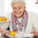 Zwei lächelnde Senioren essen Lunch im Pflegeheim