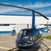 Empty rotary-wing aircraft standing on concrete landing pad before metal hangar at heliport