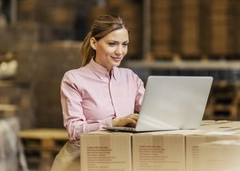 A warehouse worker controlling shipment on laptop.