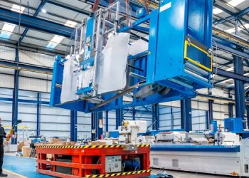 Pracownik firmy relokacyjnej podnosi za pomocą suwnicy część wyposażenia zakładu